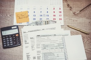 Tax form with calendar, pen, calculator, notepad and glasses. to