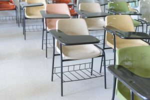 Many lecture chairs arranged neatly in empty classroom.