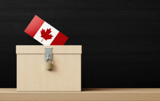 White ballot box and Canadian flag textured vote in front of blackboard. Horizontal composition. Election concept.